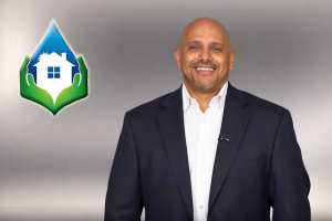 Man in a suit smiling, representing Healthy Way Waterproofing, with logo featuring a house and water droplet symbolizing moisture control and home safety.
