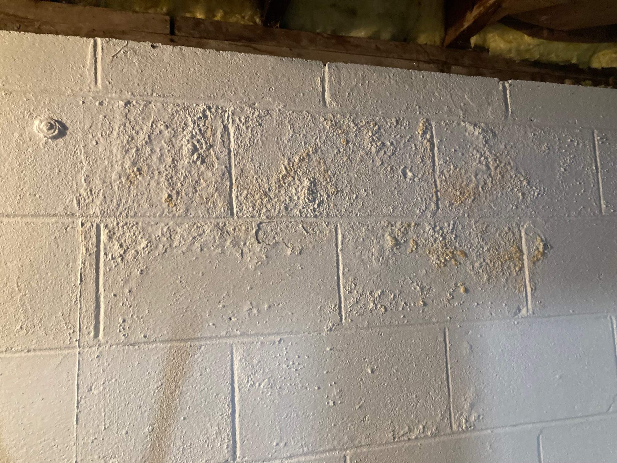 Cinder block basement wall showing cracks, moisture damage, and efflorescence buildup indicating water intrusion and foundation pressure