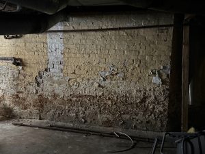 Basement wall showing signs of wear and damage, including uneven surface and potential moisture issues, relevant to foundation crack repair and structural integrity in New Jersey homes.