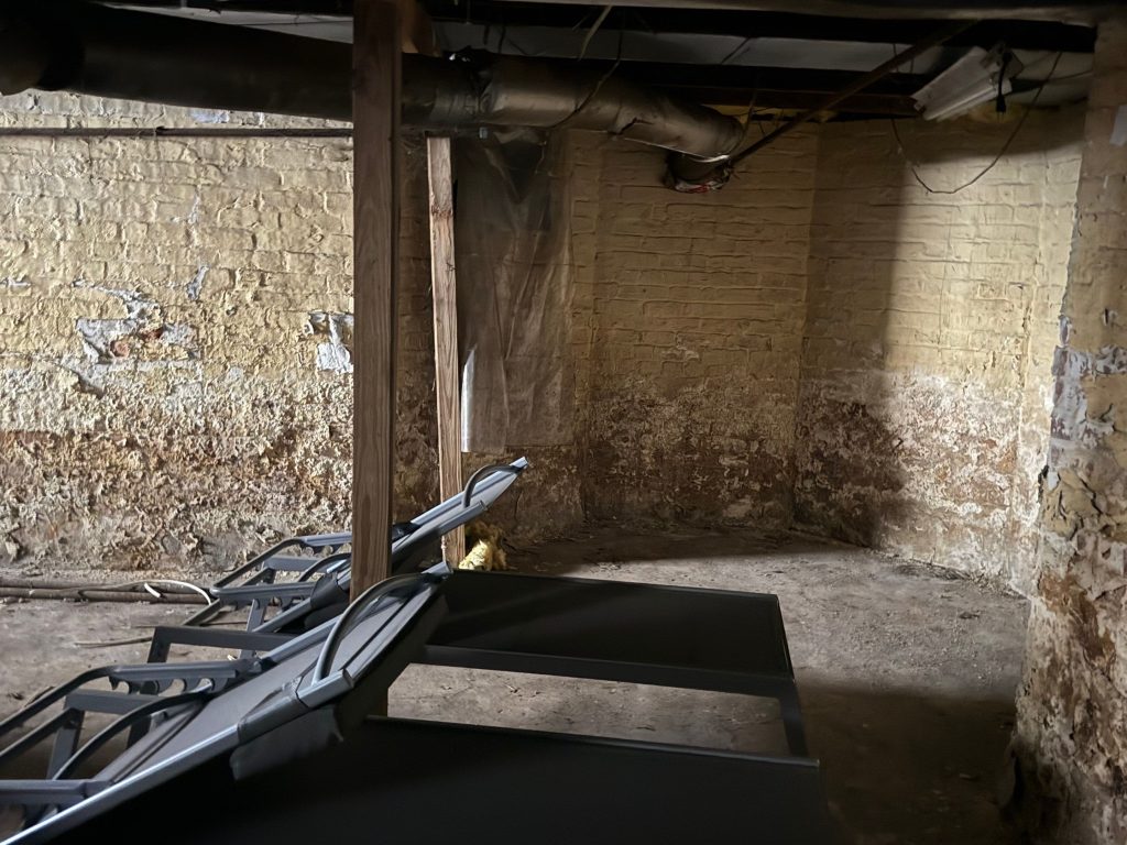 Damaged basement with exposed brick and construction equipment illustrating mold remediation and restoration in NJ.